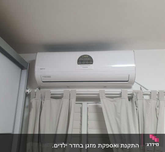 מזגן מותקן על קיר מעל חלון עם וילונות